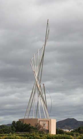 Escultura en la calle de acero con tubos apuntando al cielo y una base de terrazo